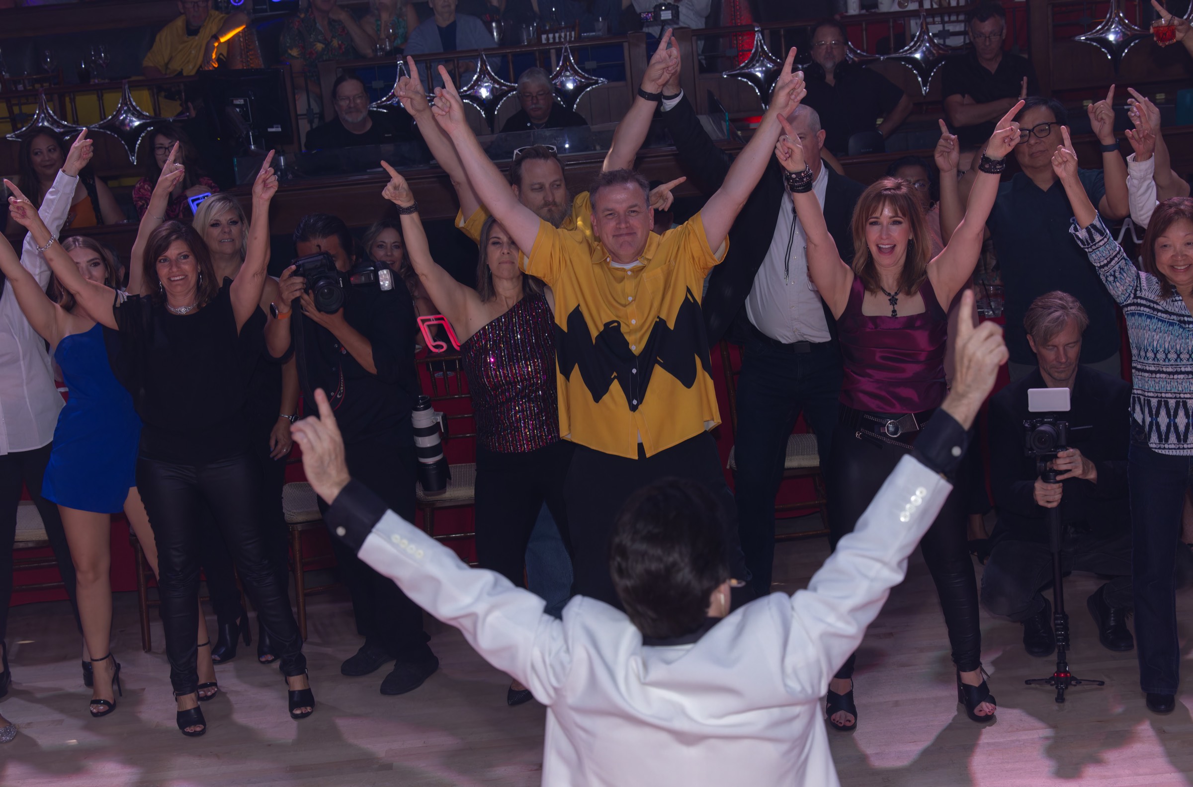 Tony making a grand entrance while guests gather and clap on the dance floor at a private event.