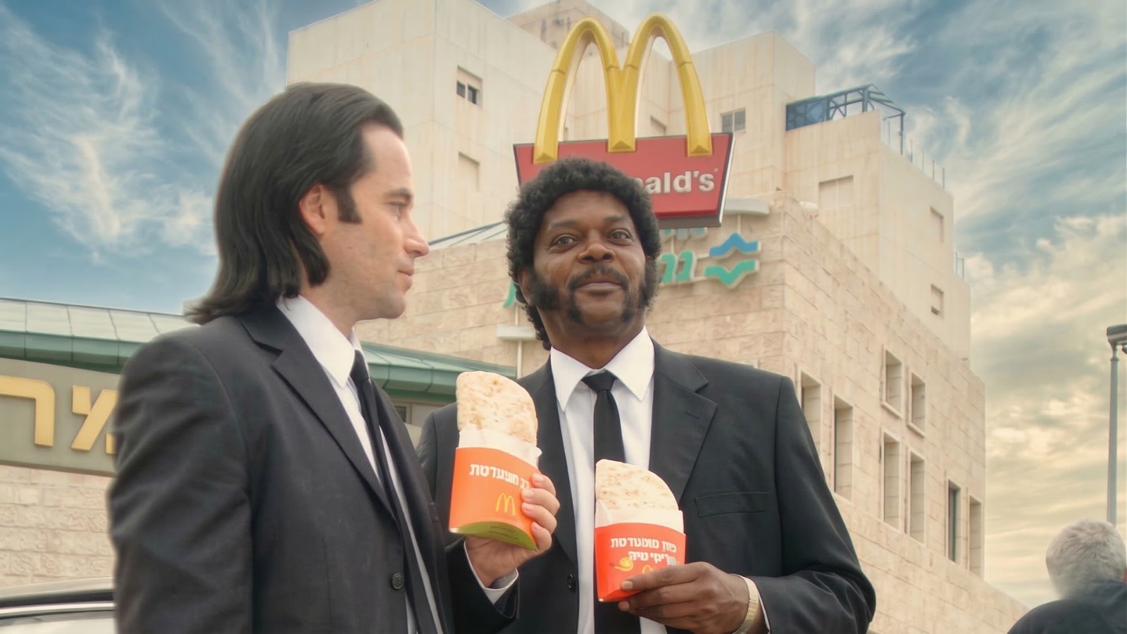 Two Pulp Fiction inspired performers in black suits posing in front of a red car